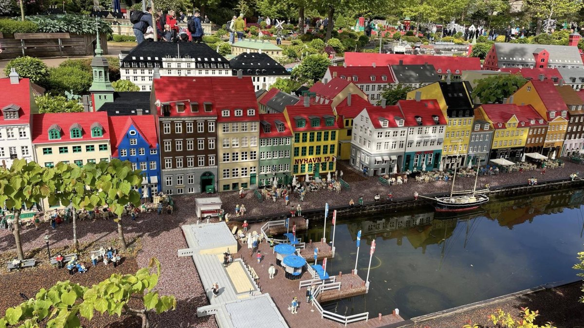 Miniaturowe budynki i figurki w Legolandzie w Billund, z widokiem na wodę i zieleń.