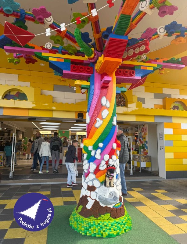 Kolorowe drzewo z klocków LEGO w Legolandzie, w tle zwiedzający i sklep.