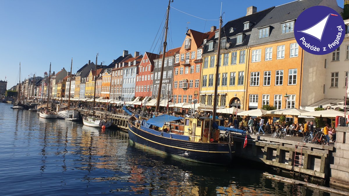Widok kolorowych kamienic nad wodą w Kopenhadze z łodziami w porcie.
